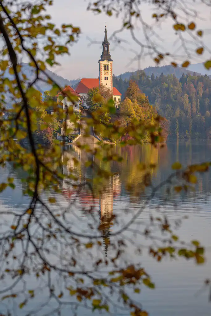 Lake Bled island as seen through the branches and autumn leaves